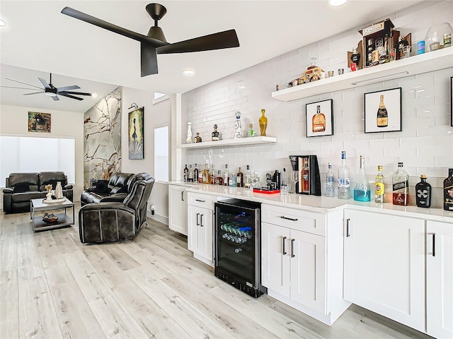 bar featuring ceiling fan, white cabinets, wine cooler, decorative backsplash, and light hardwood / wood-style flooring