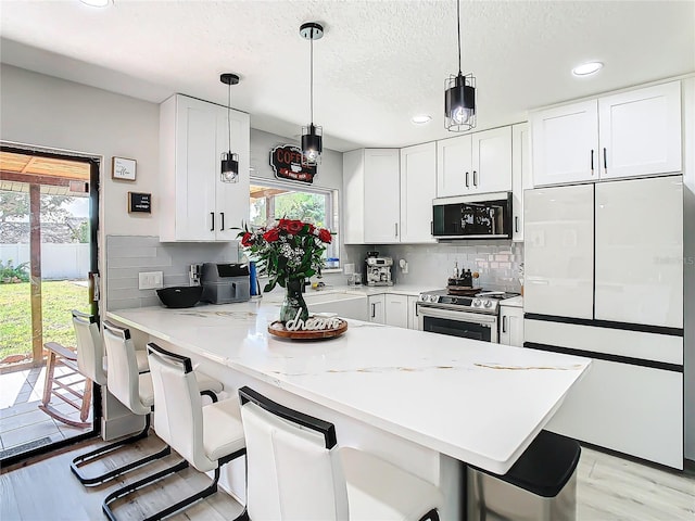 kitchen with white cabinetry, electric stove, a kitchen bar, and white refrigerator