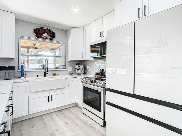 kitchen with tasteful backsplash, white cabinetry, light wood-type flooring, sink, and stainless steel appliances