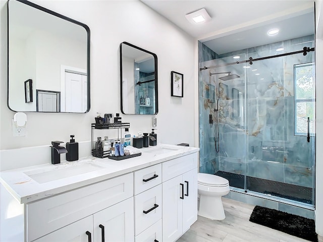 bathroom with vanity, toilet, wood-type flooring, and a shower with shower door