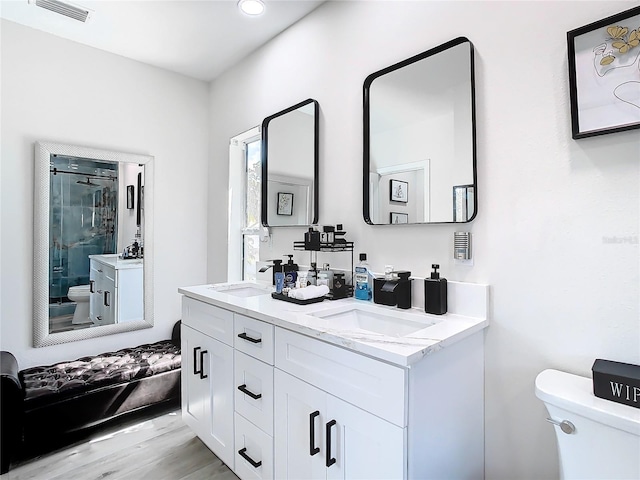 bathroom featuring a shower with door, vanity, hardwood / wood-style floors, and toilet