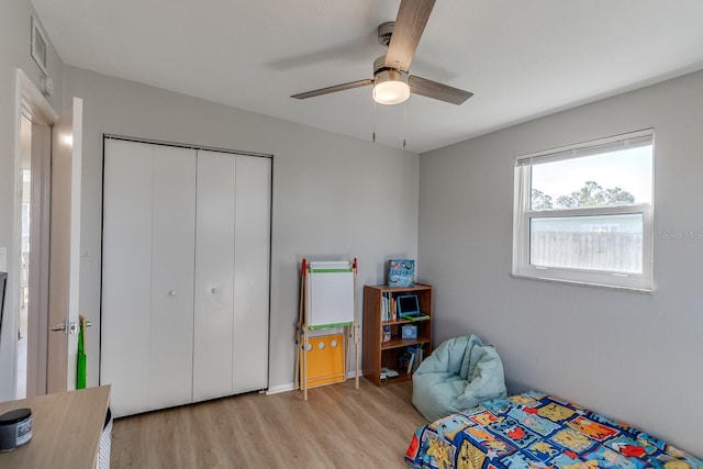 bedroom with light wood-type flooring, ceiling fan, and a closet