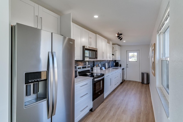 kitchen featuring backsplash, white cabinetry, stainless steel appliances, and light wood-type flooring