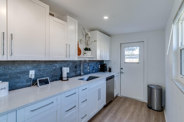 kitchen featuring tasteful backsplash, white cabinets, dishwasher, and sink