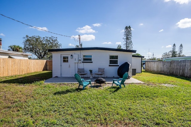 back of property with a fire pit, a lawn, and central AC