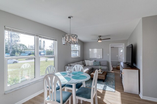 dining space with ceiling fan with notable chandelier and light wood-type flooring