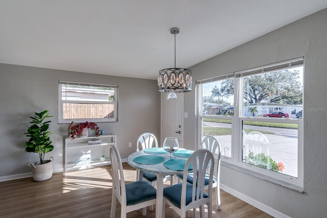 dining space featuring an inviting chandelier, lofted ceiling, and hardwood / wood-style floors