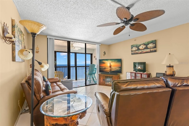 living room featuring ceiling fan, a wall of windows, a textured ceiling, and light tile patterned floors