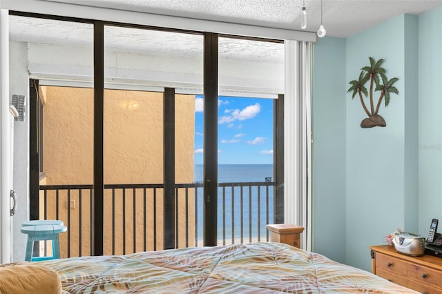 bedroom with access to exterior, a textured ceiling, and a water view