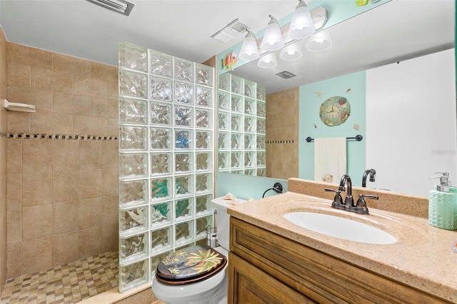 bathroom featuring tiled shower, vanity, and toilet