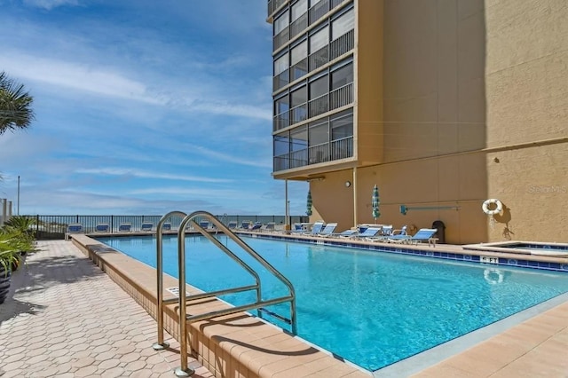 view of pool featuring a patio area, a water view, and a hot tub