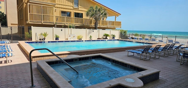 view of pool featuring a patio area, a water view, and a hot tub