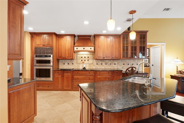 kitchen featuring custom range hood, double oven, sink, dark stone countertops, and hanging light fixtures