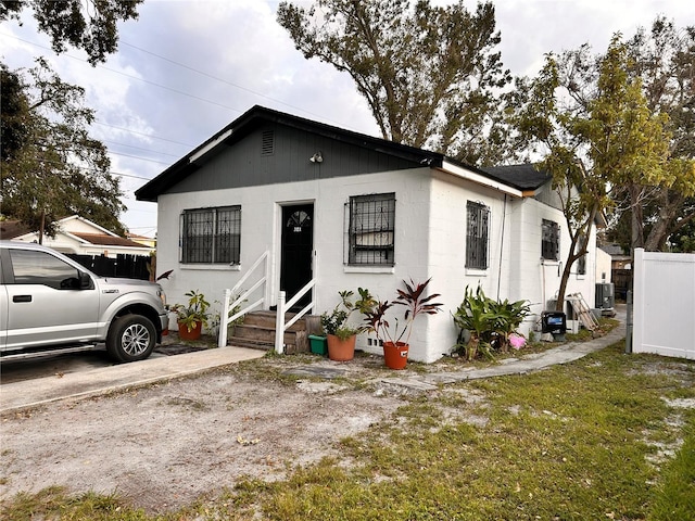 bungalow-style house with entry steps, fence, and cooling unit