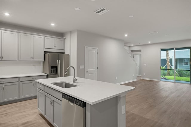 kitchen with light hardwood / wood-style flooring, stainless steel appliances, sink, and a center island with sink