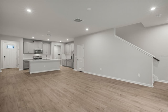 unfurnished living room featuring light hardwood / wood-style flooring and sink