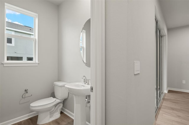 bathroom featuring a shower with door, toilet, and hardwood / wood-style flooring