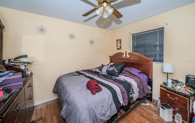 bedroom with light hardwood / wood-style flooring, a textured ceiling, and ceiling fan