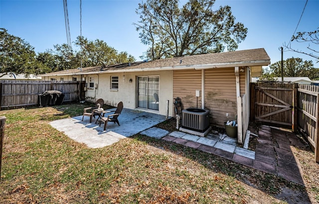 rear view of property featuring central AC unit, a patio, and a lawn