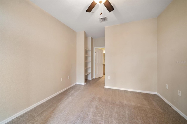 carpeted empty room featuring built in shelves and ceiling fan