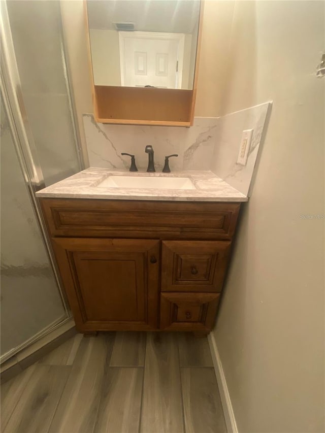 bathroom with hardwood / wood-style floors, vanity, and decorative backsplash