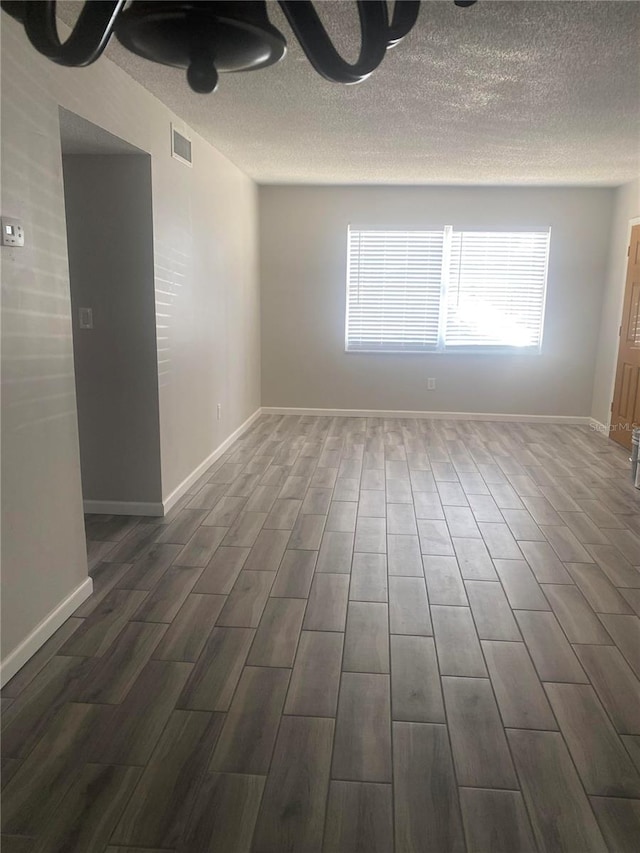 unfurnished room with dark wood-type flooring and a textured ceiling