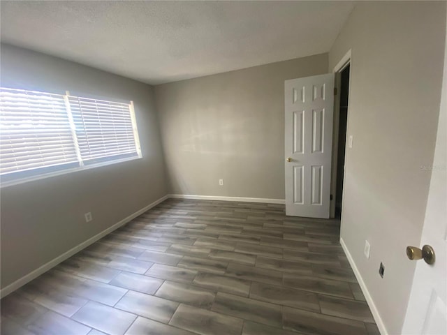 empty room with a textured ceiling and dark hardwood / wood-style flooring