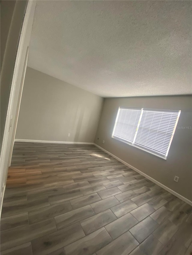 unfurnished room featuring dark wood-type flooring and a textured ceiling