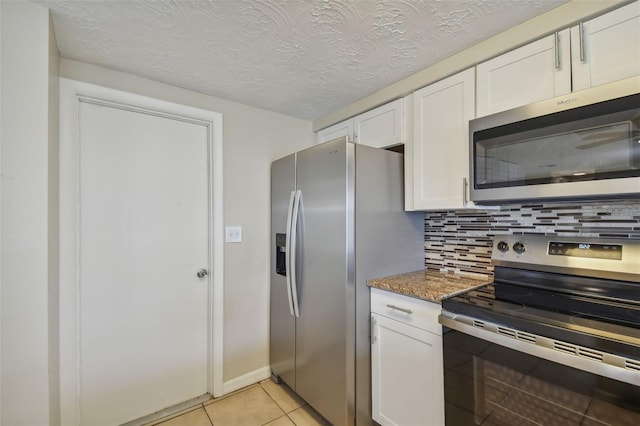 kitchen with appliances with stainless steel finishes, stone countertops, a textured ceiling, white cabinets, and decorative backsplash