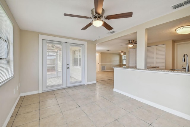 tiled empty room featuring french doors and ceiling fan