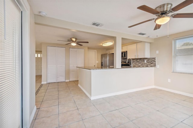 kitchen with white cabinetry, kitchen peninsula, stainless steel appliances, and light tile patterned floors