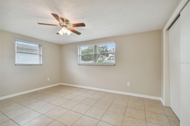 tiled spare room featuring ceiling fan