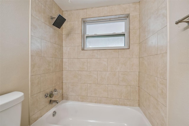 bathroom featuring toilet and tiled shower / bath combo