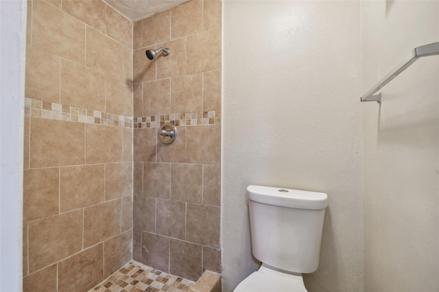 bathroom featuring a tile shower and toilet