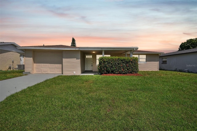 single story home featuring a yard, central AC unit, and a garage