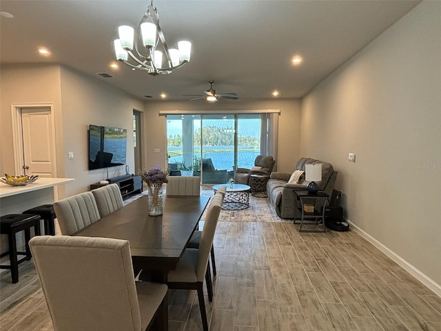 dining space with ceiling fan with notable chandelier and light wood-type flooring