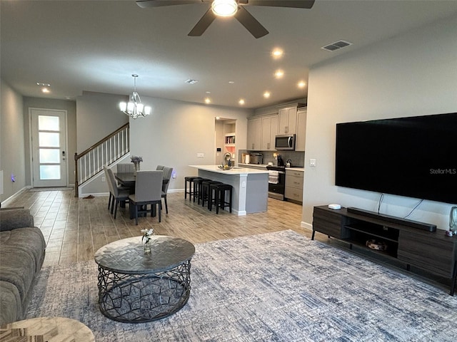 living room with light hardwood / wood-style floors and ceiling fan with notable chandelier