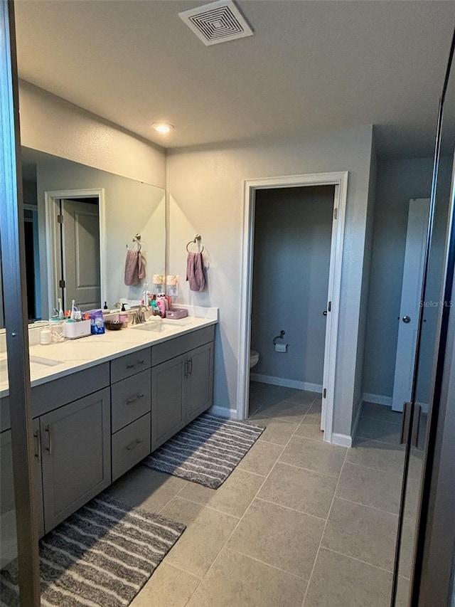 bathroom with toilet, vanity, and tile patterned flooring