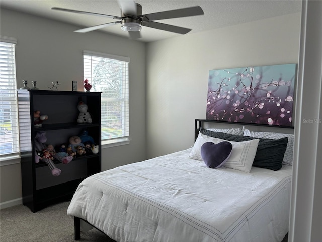 carpeted bedroom featuring ceiling fan and a textured ceiling