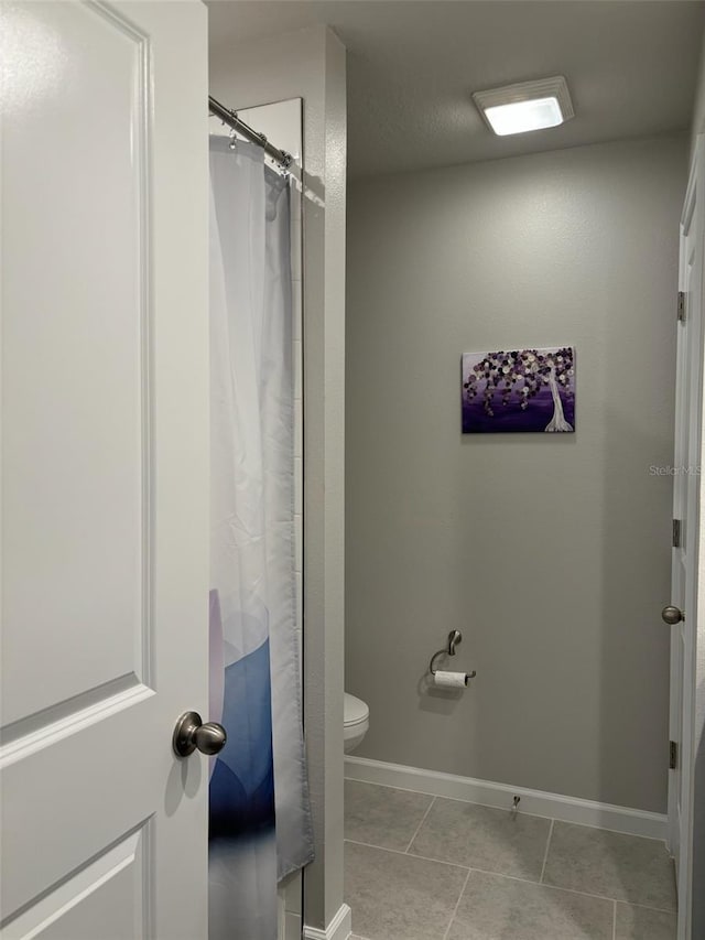 bathroom with toilet, curtained shower, and tile patterned flooring