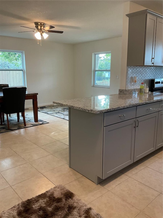 kitchen with gray cabinetry, light stone counters, and a healthy amount of sunlight