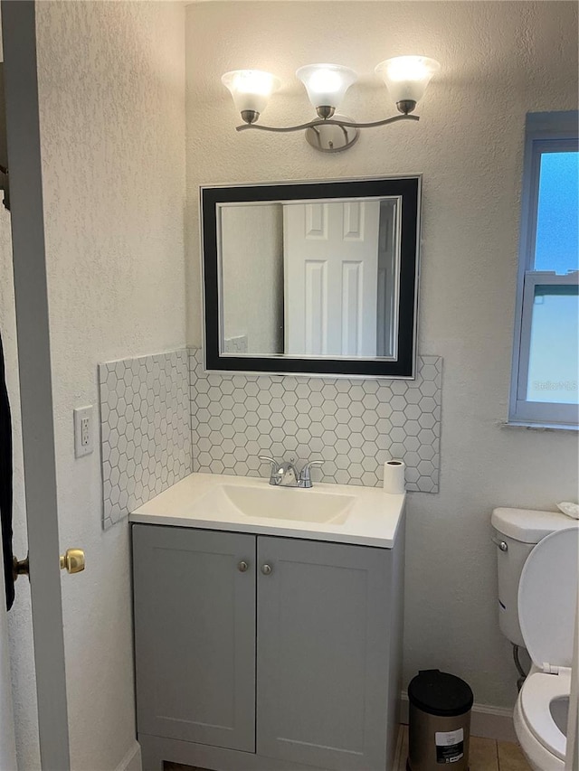 bathroom with vanity, toilet, and tasteful backsplash