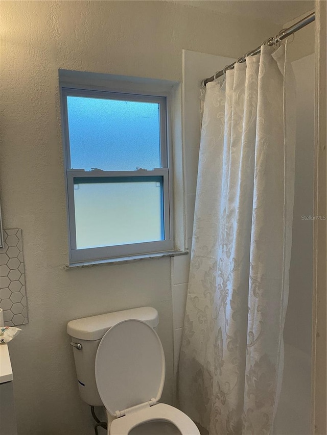 bathroom with a shower with curtain and toilet