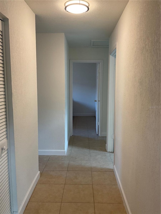 hall featuring a textured ceiling and light tile patterned floors