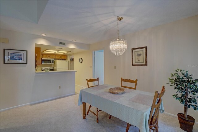 dining room with a chandelier and light colored carpet