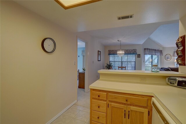 kitchen with lofted ceiling, a notable chandelier, pendant lighting, and light tile patterned floors