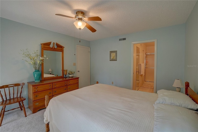 carpeted bedroom with a textured ceiling, ensuite bathroom, and ceiling fan