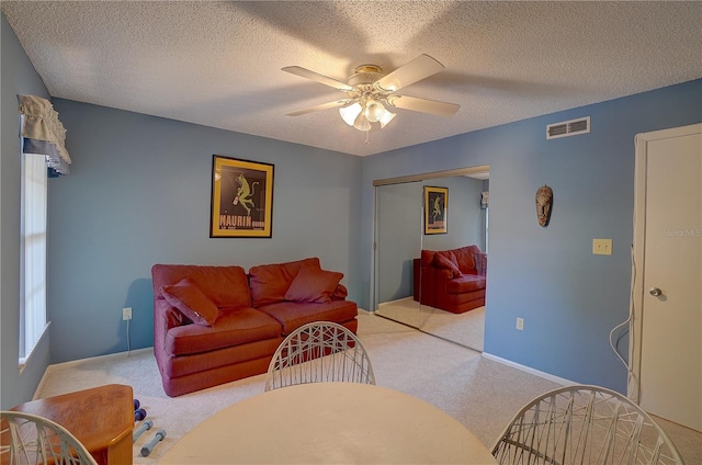 living room featuring a textured ceiling, light colored carpet, and ceiling fan