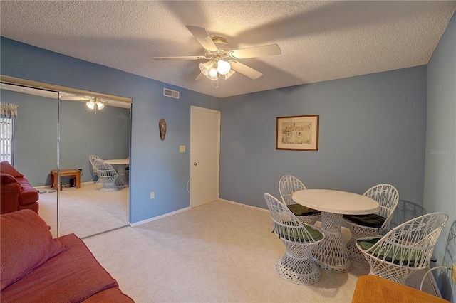 carpeted dining space featuring a textured ceiling and ceiling fan