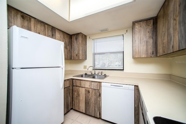 kitchen featuring light tile patterned flooring, a sink, white appliances, light countertops, and visible vents
